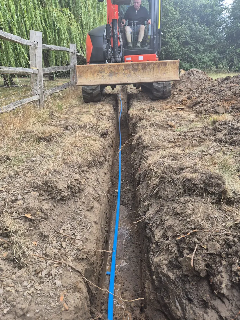 Excavator digging a service trench on a Malling Utilities site